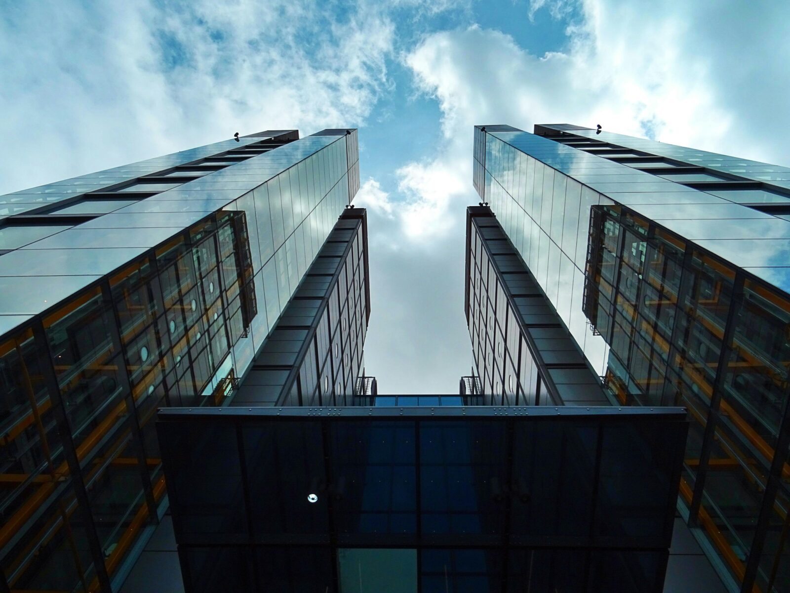 Low-angle view of sleek, modern skyscrapers with glass facades under a blue sky.
