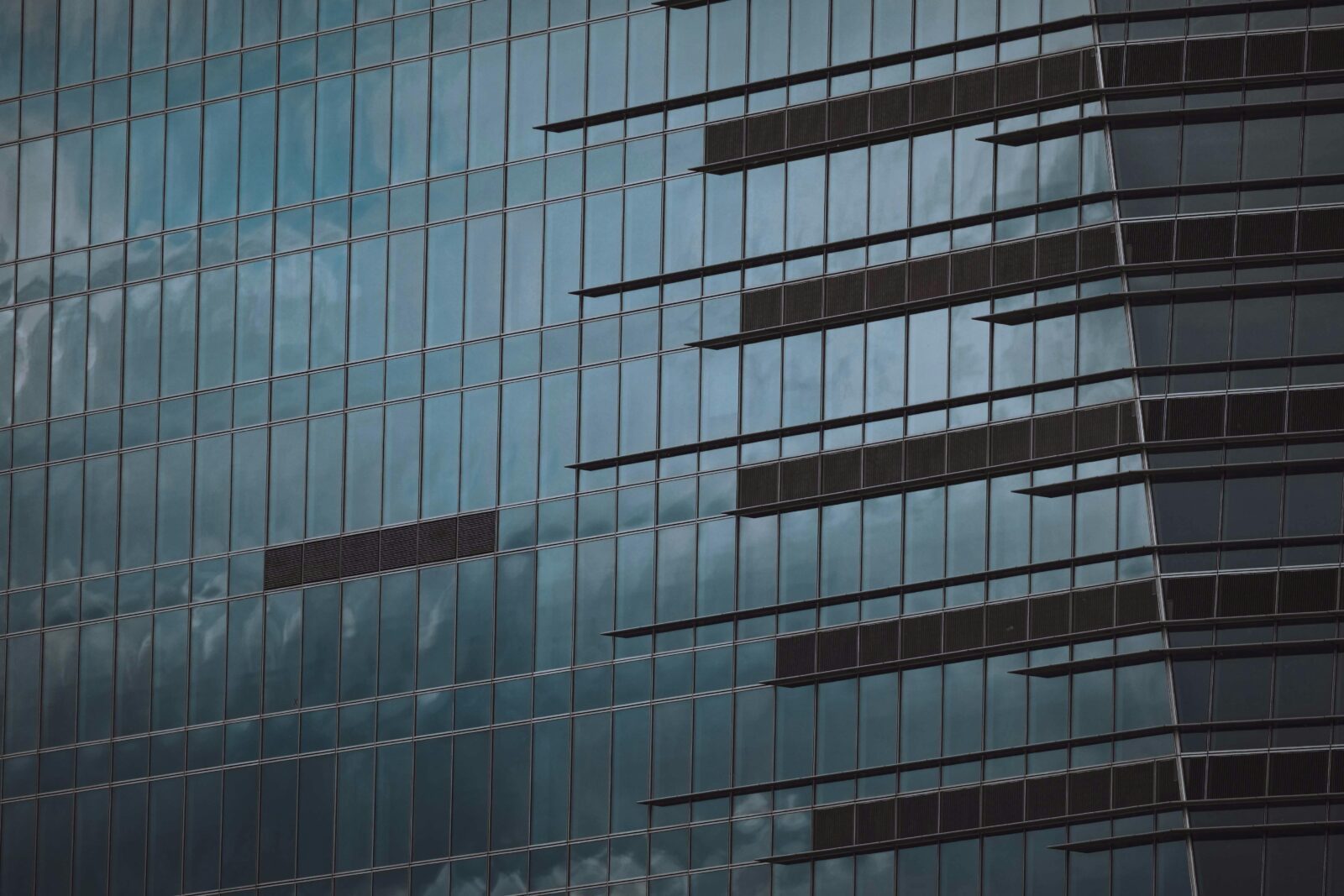 Close-up view of modern glass facade with reflections on an urban skyscraper.